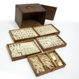 A MAHJONG SET, the painted ivorine pieces contained in a five drawer oak cabinet with sliding
