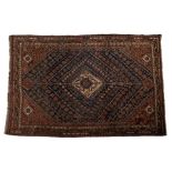 AN OLD QASHGAI BLUE GROUND RUG with a central hooked medallion in a radiating diamond design and