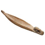 A PAPUA NEW GUINEA CARVED WOODEN FEAST BOWL in the form of a canoe with shaped prow and stylised