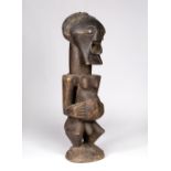 A SONGYE POWER FIGURE, Democratic Republic of the Congo, carved wood 'NKISHI' standing on a circular