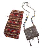 A MOROCCAN LEATHER SADDLE BAG with embossed decoration and a polychrome textile saddle bag with