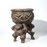 A AFRICAN NAIVELY CARVED WOODEN FEAST BOWL, with supporting figures 33cm high