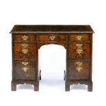AN 18TH CENTURY WALNUT KNEEHOLE DESK, the quarter veneered top within a feather banded border