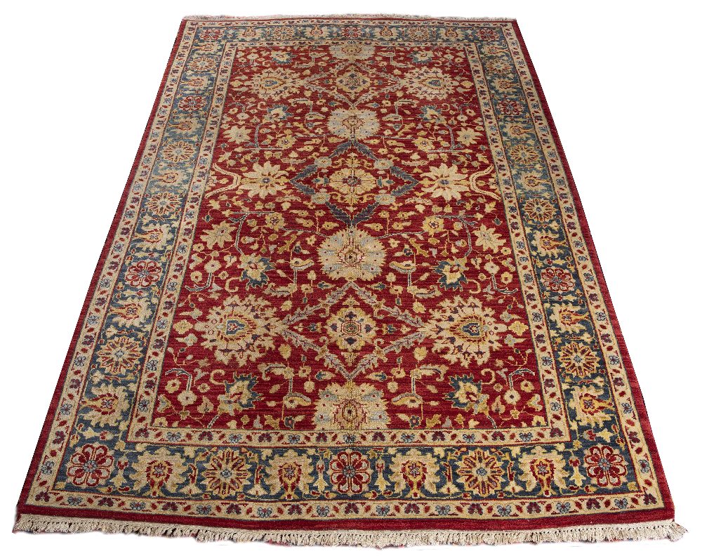 AN AGRA RED GROUND CARPET the repeating foliate and scroll motif within a dark blue ground border,