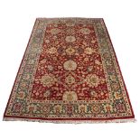 AN AGRA RED GROUND CARPET the repeating foliate and scroll motif within a dark blue ground border,