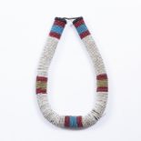 A ZULU NECKLACE with alternating rows of white, red and blue beads