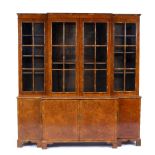 A WALNUT VENEERED BREAK FRONT LIBRARY BOOKCASE fitted an arrangement of shelves enclosed by glazed