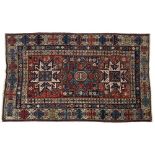 A SHIRVAN BRICK RED GROUND RUG decorated three central star medallions within a multicoloured triple