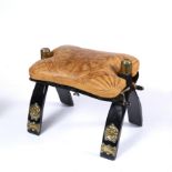 A MIDDLE EASTERN EBONIZED WOOD AND BRASS MOUNTED CAMEL SADDLE STOOL with a leather cushion 33cm high