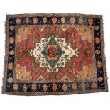 AN EASTERN, HERIZ STYLE BRICK RED GROUND RUG with a central medallion within a blue ground border,