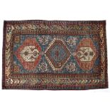 A SHIRVAN BLUE GROUND RUG decorated three medallions within a multicoloured hooked border, 194cm x