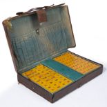 A BONE MAHJONG SET probably bakelite or similar material, contained within a leather carrying case