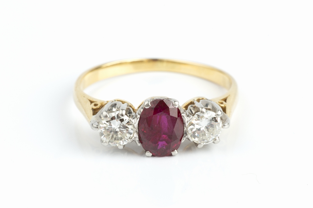 A RUBY AND DIAMOND THREE STONE RING, the oval mixed-cut ruby claw set between two round brilliant-