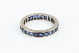 A SAPPHIRE FULL HOOP ETERNITY RING, channel set throughout with square step-cut sapphires, white