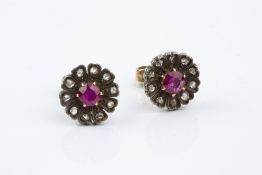A PAIR OF RUBY AND DIAMOND CLUSTER EAR STUDS, each designed as a flowerhead cluster, centred with