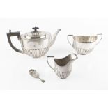 A SILVER THREE PIECE TEA SERVICE, of oval half lobed form, the teapot with ebonised handle and knop,
