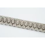 A DIAMOND SET PANEL BRACELET, designed as a line of articulated geometric panels, each millegrain