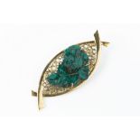 A SYNTHETIC EMERALD CRYSTAL BROOCH/PENDANT, the abstract navette-shaped panel decorated with pierced