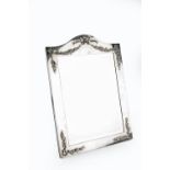 AN EDWARDIAN SILVER EASEL DRESSING TABLE MIRROR, with arched top, applied with ribbon tied