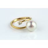 A CULTURED PEARL AND DIAMOND DRESS RING, of crossover design, yellow precious metal mounted, stamped