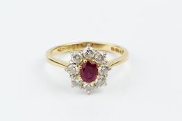 A RUBY AND DIAMOND CLUSTER RING, the oval mixed-cut ruby claw set within a border of round