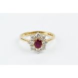 A RUBY AND DIAMOND CLUSTER RING, the oval mixed-cut ruby claw set within a border of round