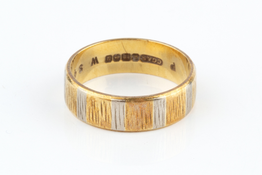 AN 18CT THREE COLOUR GOLD WEDDING BAND, of textured flat section design, ring size O