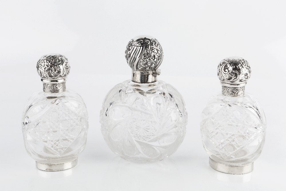 A LATE VICTORIAN SILVER TOPPED CUT GLASS SCENT BOTTLE, the hinged top repoussé decorated with