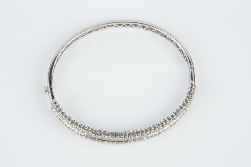 A DIAMOND BANGLE, of hinged oval form, channel set to the front with a line of baguette-cut - Image 5 of 5