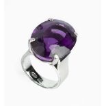 AN AMETHYST SINGLE STONE RING, the oval mixed-cut amethyst in four claw setting, white precious