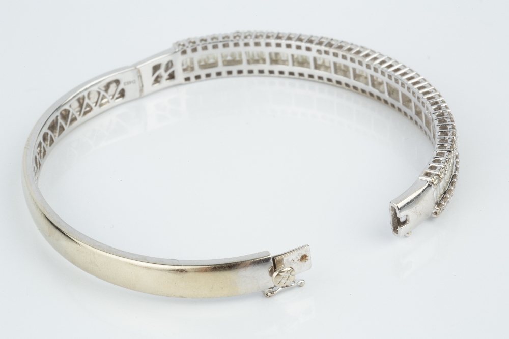 A DIAMOND BANGLE, of hinged oval form, channel set to the front with a line of baguette-cut - Image 4 of 5