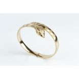 A 9CT GOLD SERPENT BANGLE, of hinged crossover design, with circular-cut red stone eyes and engraved