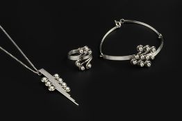 A DIAMOND SET PENDANT, BRACELET AND RING SUITE, of abstract scrolled design, each collet set with
