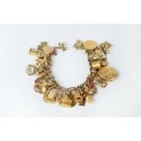 A CHARM BRACELET, the yellow precious metal fancy-link bracelet suspending a collection of