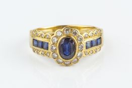 A SAPPHIRE AND DIAMOND CLUSTER RING, centred with an oval mixed-cut sapphire and round brilliant-cut