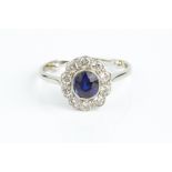 A SAPPHIRE AND DIAMOND CLUSTER RING, the cushion-shaped mixed-cut sapphire in millegrain collet