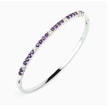 AN AMETHYST AND DIAMOND LINE BANGLE, the oval hinged bangle claw set with a line of circular mixed-
