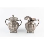 A MEXICAN SILVER TWIN HANDLED SUCRIER AND COVER, and matching milk jug, with shaped foliate cast