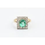 AN EMERALD AND DIAMOND CLUSTER RING, the octagonal step-cut emerald claw set within a border of