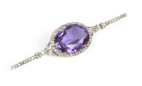 AN AMETHYST AND DIAMOND CLUSTER BAR BROOCH, centred with an oval mixed-cut amethyst bordered by