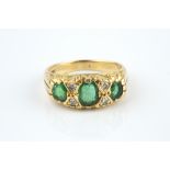 AN EMERALD AND DIAMOND HALF HOOP RING, the graduated oval mixed-cut emeralds spaced by pairs of