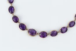 AN AMETHYST RIVIÈRE NECKLACE, comprising a line of graduated oval mixed-cut amethysts in pinched
