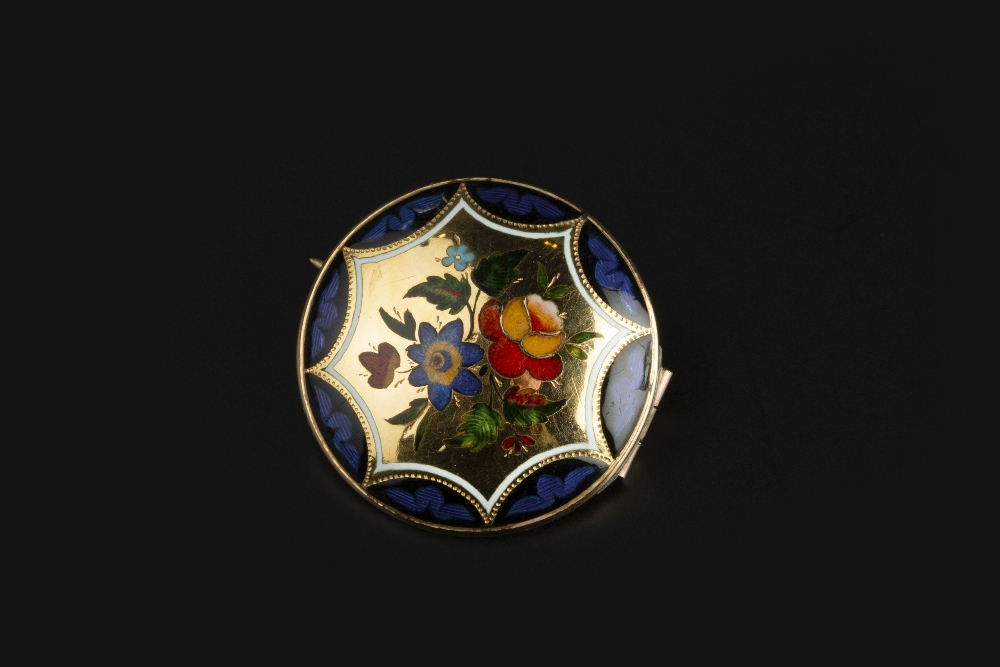 AN ENAMEL PANEL BROOCH, the circular convex panel decorated with a spray of polychrome enamel