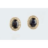 A PAIR OF SAPPHIRE AND DIAMOND CLUSTER EAR STUDS, each oval mixed-cut sapphire claw set within a
