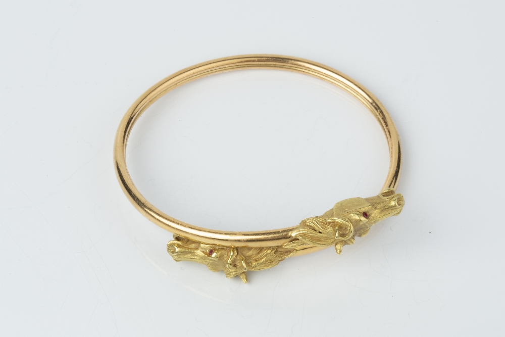 AN 18CT GOLD BANGLE, of crossover design, the horse's head terminals with red stone eyes, with - Image 2 of 2