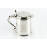 A SILVER TANKARD, of plain, slightly tapered form, the hinged cover with shaped thumbpiece, and