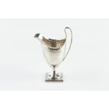 A GEORGE III SILVER HELMET SHAPED CREAM JUG, with punched border and bright cut decoration, on