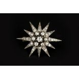 A DIAMOND STAR BROOCH, centred with a tiered cluster of old-cut diamonds, bordered by rays of