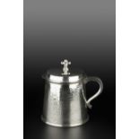 A SILVER TANKARD of slightly tapered, planished form, the hinged cover with fleur de lys finial,