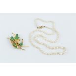 A JADE SPRAY BROOCH, modelled as a pierced and scrolled ribbon with a spray of oval and pear-